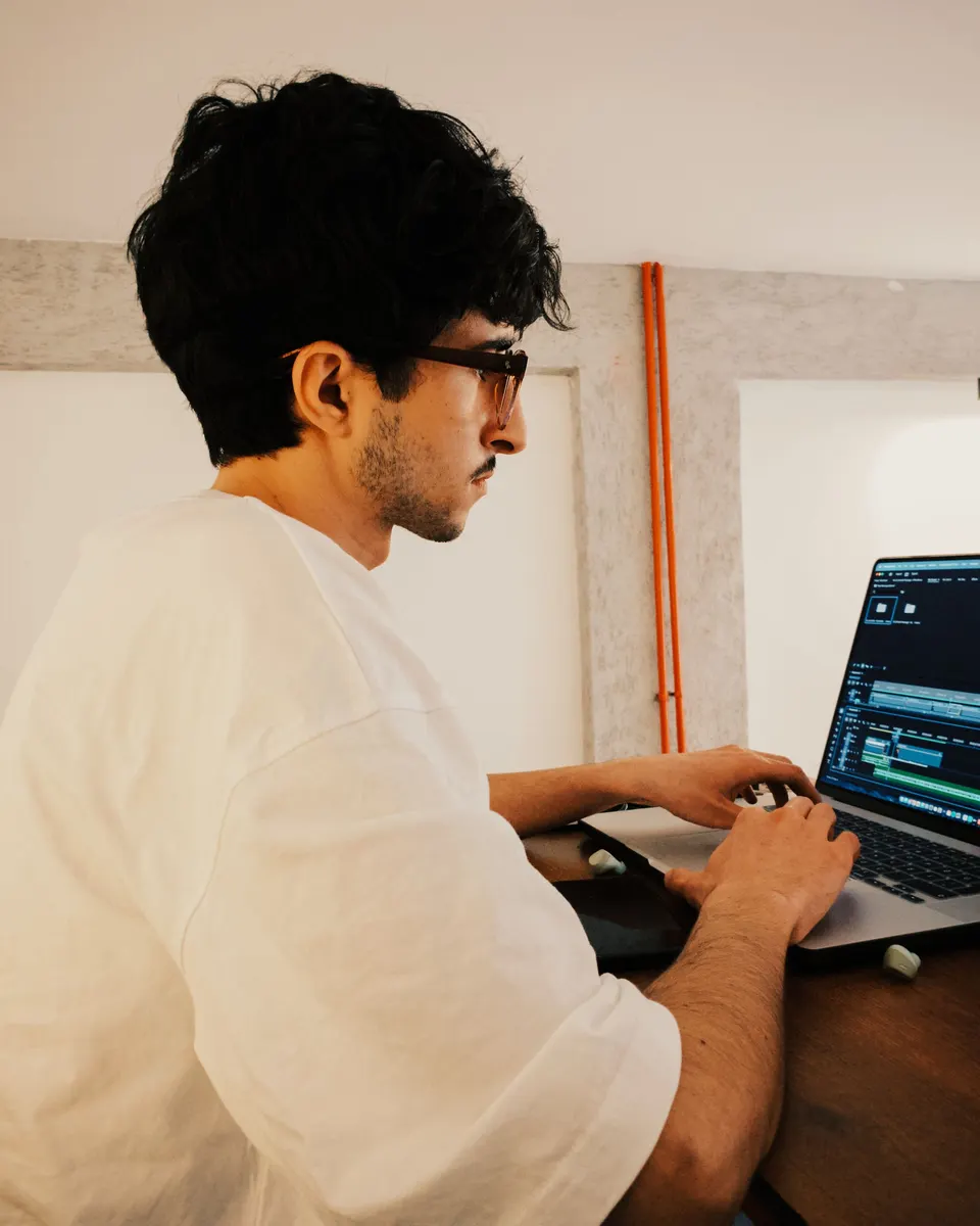 A young man editing a video timeline on a laptop