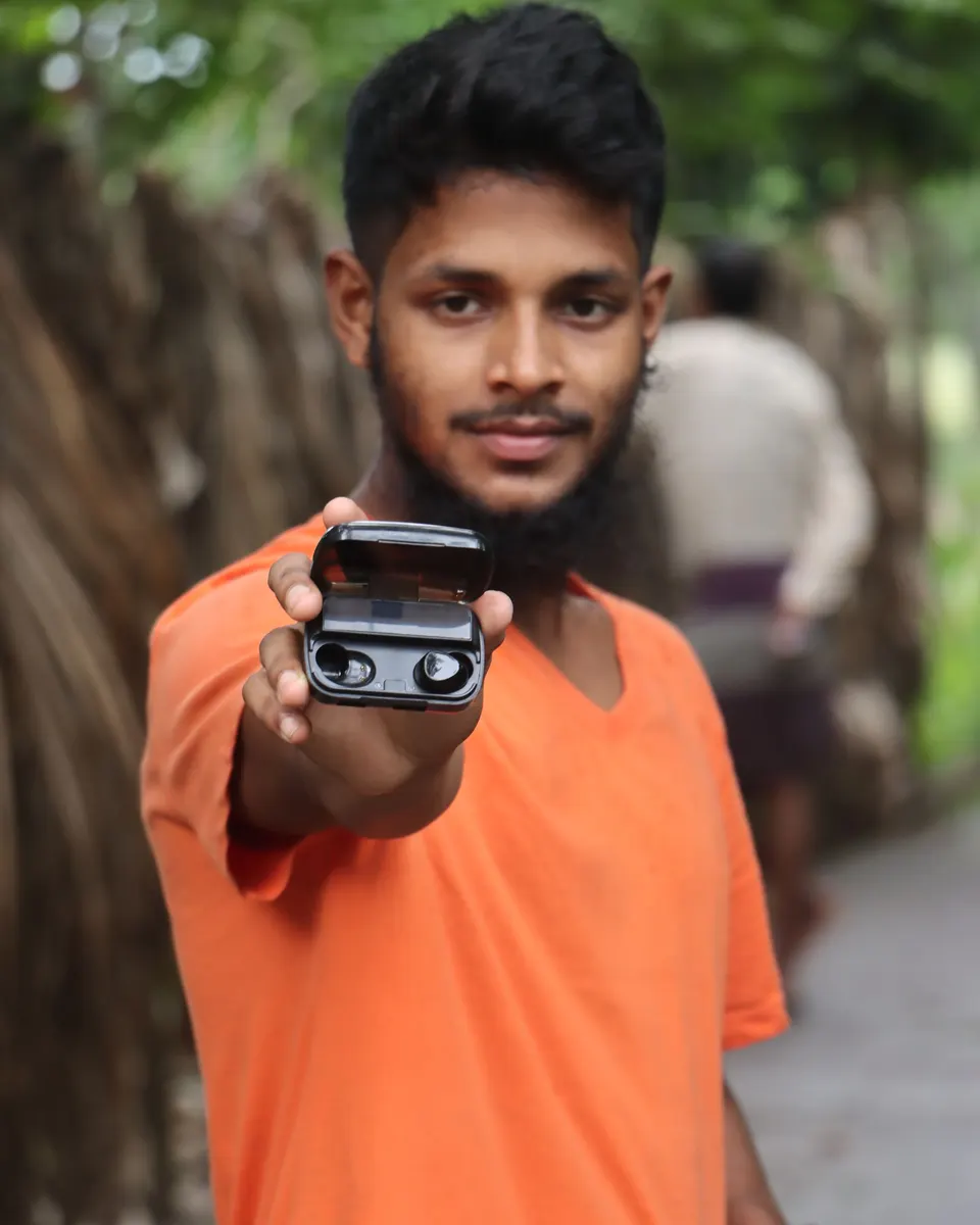 A man holding out an earbuds case to the camera