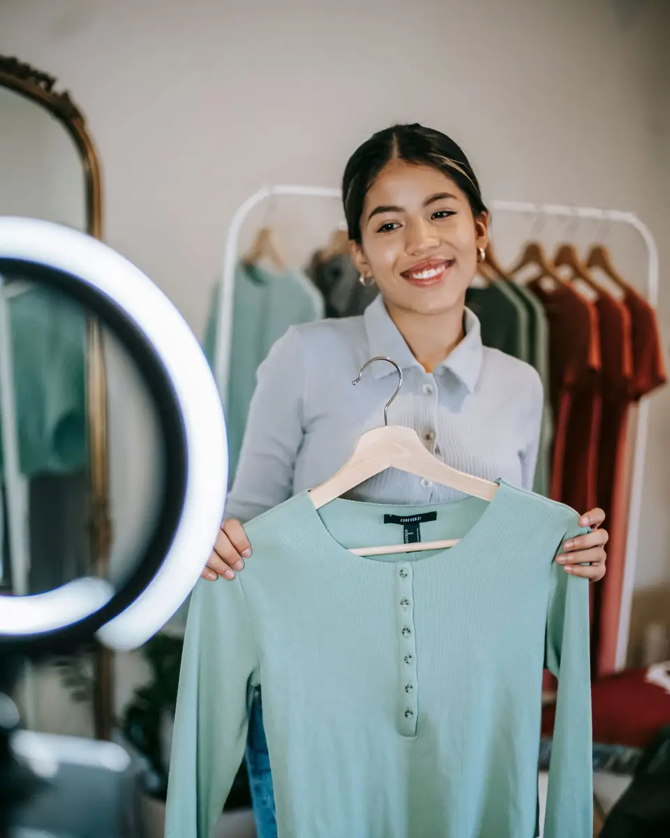 A creator holding up a top on a hanger in front of a ring light