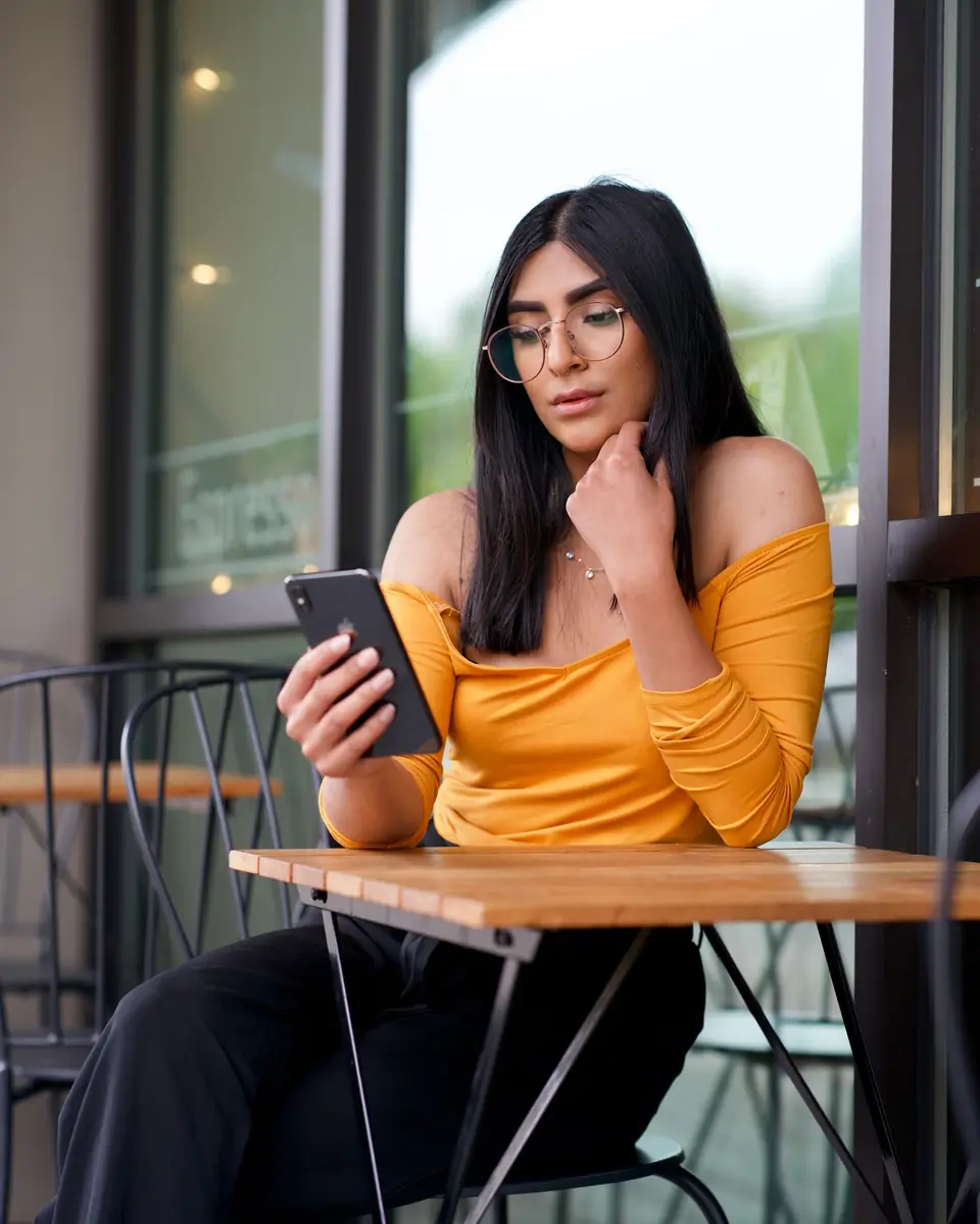 A young woman checking her phone at a café table