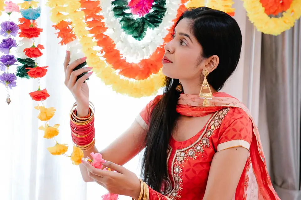 A young woman in a red suit hanging flower garlands at home