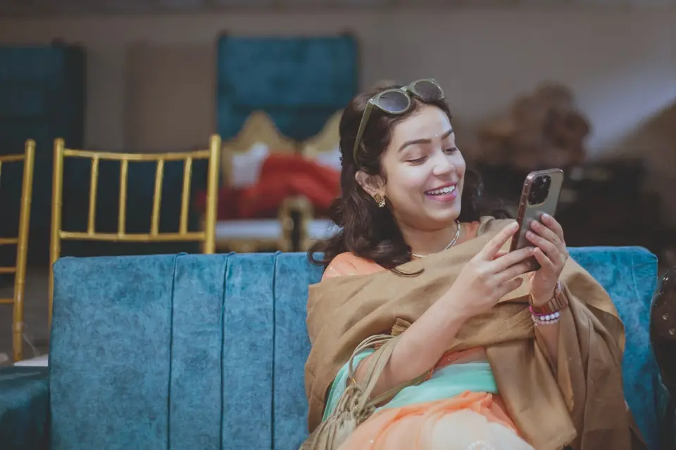 A young woman smiling at her phone on a sofa