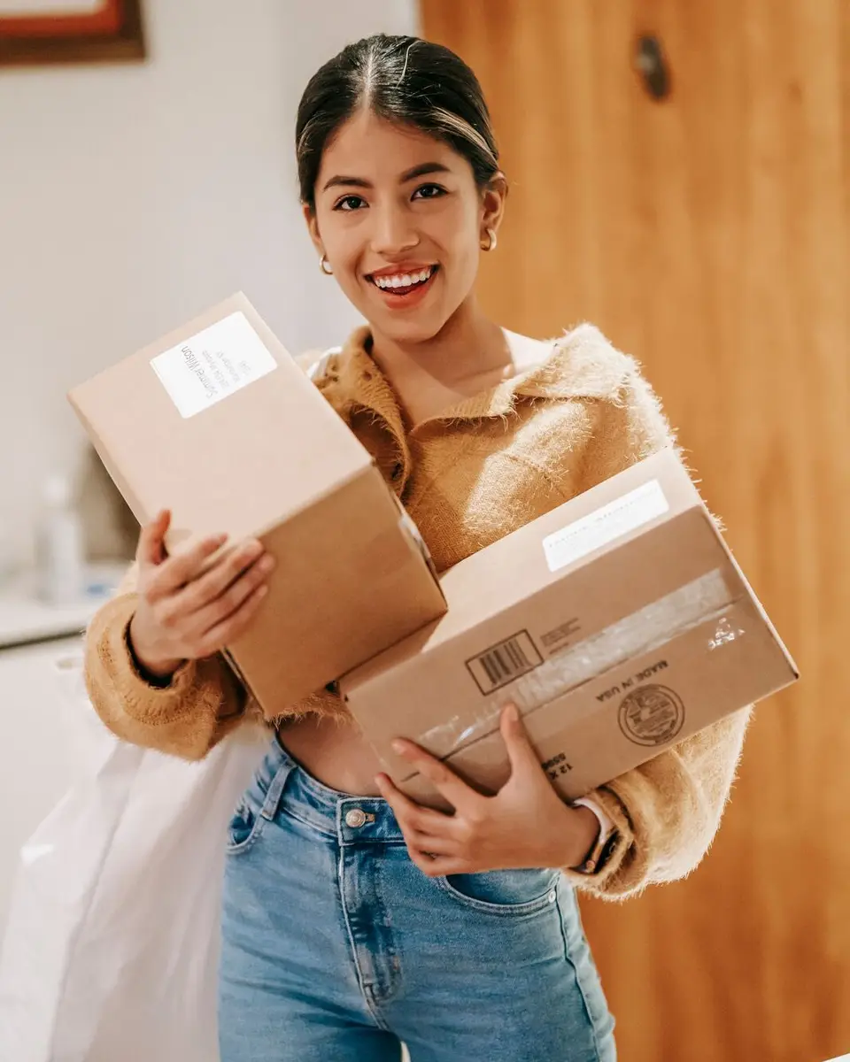 A smiling woman at home holding two delivered parcels